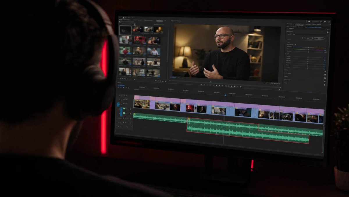Monteur de dos avec un casque, face à un grand écran de montage : une interview à l’image et, sur la timeline, une piste audio qui dépasse sous le plan suivant, entourée de rouge