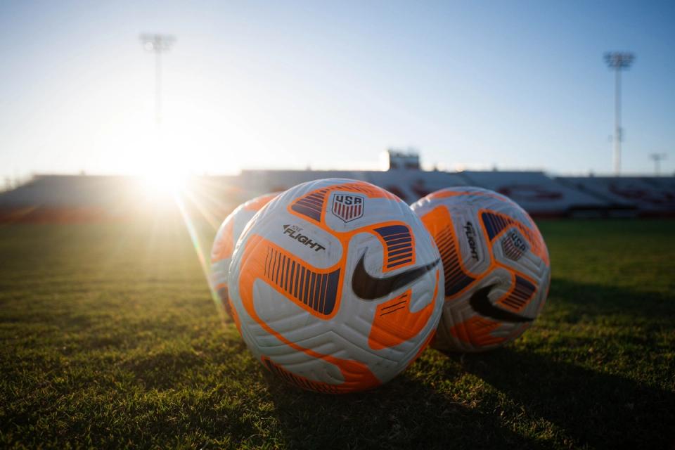 Soccer balls on the pitch with the sun in the background