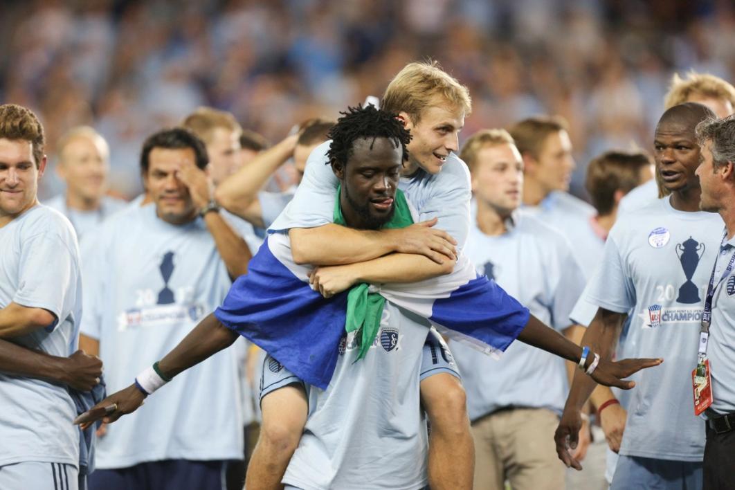 Kei Kamara with a player on his back and other players in background all wearing Sporting Kansas City Open Cup shirts​​​​‌﻿‍﻿​‍​‍‌‍﻿﻿‌﻿​‍‌‍‍‌‌‍‌﻿‌‍‍‌‌‍﻿‍​‍​‍​﻿‍‍​‍​‍‌﻿​﻿‌‍​‌‌‍﻿‍‌‍‍‌‌﻿‌​‌﻿‍‌​‍﻿‍‌‍‍‌‌‍﻿﻿​‍​‍​‍﻿​​‍​‍‌‍‍​‌﻿​‍‌‍‌‌‌‍‌‍​‍​‍​﻿‍‍​‍​‍‌‍‍​‌﻿‌​‌﻿‌​‌﻿​​‌﻿​﻿​﻿‍‍​‍﻿﻿​‍﻿﻿‌﻿‌‌‌﻿​﻿‌﻿​﻿‌‍‌‍​‍﻿‍‌﻿​﻿‌‍​‌‌‍﻿‍‌‍‍‌‌﻿‌​‌﻿‍‌​‍﻿‍‌﻿​﻿‌﻿‌​‌﻿‌‌‌‍‌​‌‍‍‌‌‍﻿﻿​‍﻿﻿‌‍‍‌‌‍﻿‍‌﻿‌​‌‍‌‌‌‍﻿‍‌﻿‌​​‍﻿﻿‌‍‌‌‌‍‌​‌‍‍‌‌﻿‌​​‍﻿﻿‌‍﻿‌‌‍﻿﻿‌‍‌​‌‍‌‌​﻿﻿‌‌﻿​​‌﻿​‍‌‍‌‌‌﻿​﻿‌‍‌‌‌‍﻿‍‌﻿‌​‌‍​‌‌﻿‌​‌‍‍‌‌‍﻿﻿‌‍﻿‍​﻿‍﻿‌‍‍‌‌‍‌​​﻿﻿‌‌‍​‍​﻿‍​​﻿‌​​﻿​​​﻿‌﻿​﻿‌‌​﻿‌‍‌‍​‍​‍﻿‌​﻿​‌‌‍‌​​﻿​‍​﻿‌﻿​‍﻿‌​﻿‌​​﻿​‌​﻿‌﻿‌‍‌‌​‍﻿‌​﻿‍‌‌‍‌‌‌‍‌​​﻿‌​​‍﻿‌‌‍‌​​﻿​‍​﻿‍‌‌‍‌‌​﻿​‌​﻿‍‌‌‍‌​​﻿​​‌‍‌‍‌‍​‌‌‍​﻿‌‍​﻿​﻿‍﻿‌﻿‌​‌﻿‍‌‌﻿​​‌‍‌‌​﻿﻿‌‌﻿​﻿‌﻿‌​‌‍﻿﻿‌﻿​‍‌﻿‍‌​﻿‍﻿‌﻿​​‌‍​‌‌﻿‌​‌‍‍​​﻿﻿‌‌‍​﻿‌‍﻿﻿‌‍﻿‍‌﻿‌​‌‍‌‌‌‍﻿‍‌﻿‌​​‍‌‌​﻿‌‌‌​​‍‌‌﻿﻿‌‍‍﻿‌‍‌‌‌﻿‍‌​‍‌‌​﻿​﻿‌​‌​​‍‌‌​﻿​﻿‌​‌​​‍‌‌​﻿​‍​﻿​‍​﻿‌‍​﻿‌‍​﻿​‍​﻿‌​‌‍‌‍‌‍​‍‌‍‌​‌‍​‌​﻿​﻿​﻿‍‌‌‍​‍​﻿‌﻿​‍‌‌​﻿​‍​﻿​‍​‍‌‌​﻿‌‌‌​‌​​‍﻿‍‌‍‍‌‌‍﻿‌‌‍​‌‌‍‌﻿‌‍‌‌‌​‌​‌‍‌‌‌﻿​﻿‌‍‍﻿‌﻿‌​‌‍﻿﻿‌﻿​​​‍﻿‍‌‍​‌‌‍﻿​‌﻿‌​​﻿﻿﻿‌‍​‍‌‍​‌‌﻿​﻿‌‍‌‌‌‌‌‌‌﻿​‍‌‍﻿​​﻿﻿‌‌‍‍​‌﻿‌​‌﻿‌​‌﻿​​‌﻿​﻿​‍‌‌​﻿​﻿‌​​‌​‍‌‌​﻿​‍‌​‌‍​‍‌‌​﻿​‍‌​‌‍‌﻿‌‌‌﻿​﻿‌﻿​﻿‌‍‌‍​‍﻿‍‌﻿​﻿‌‍​‌‌‍﻿‍‌‍‍‌‌﻿‌​‌﻿‍‌​‍﻿‍‌﻿​﻿‌﻿‌​‌﻿‌‌‌‍‌​‌‍‍‌‌‍﻿﻿​‍‌‍‌‍‍‌‌‍‌​​﻿﻿‌‌‍​‍​﻿‍​​﻿‌​​﻿​​​﻿‌﻿​﻿‌‌​﻿‌‍‌‍​‍​‍﻿‌​﻿​‌‌‍‌​​﻿​‍​﻿‌﻿​‍﻿‌​﻿‌​​﻿​‌​﻿‌﻿‌‍‌‌​‍﻿‌​﻿‍‌‌‍‌‌‌‍‌​​﻿‌​​‍﻿‌‌‍‌​​﻿​‍​﻿‍‌‌‍‌‌​﻿​‌​﻿‍‌‌‍‌​​﻿​​‌‍‌‍‌‍​‌‌‍​﻿‌‍​﻿​‍‌‍‌﻿‌​‌﻿‍‌‌﻿​​‌‍‌‌​﻿﻿‌‌﻿​﻿‌﻿‌​‌‍﻿﻿‌﻿​‍‌﻿‍‌​‍‌‍‌﻿​​‌‍​‌‌﻿‌​‌‍‍​​﻿﻿‌‌‍​﻿‌‍﻿﻿‌‍﻿‍‌﻿‌​‌‍‌‌‌‍﻿‍‌﻿‌​​‍‌‌​﻿‌‌‌​​‍‌‌﻿﻿‌‍‍﻿‌‍‌‌‌﻿‍‌​‍‌‌​﻿​﻿‌​‌​​‍‌‌​﻿​﻿‌​‌​​‍‌‌​﻿​‍​﻿​‍​﻿‌‍​﻿‌‍​﻿​‍​﻿‌​‌‍‌‍‌‍​‍‌‍‌​‌‍​‌​﻿​﻿​﻿‍‌‌‍​‍​﻿‌﻿​‍‌‌​﻿​‍​﻿​‍​‍‌‌​﻿‌‌‌​‌​​‍﻿‍‌‍‍‌‌‍﻿‌‌‍​‌‌‍‌﻿‌‍‌‌‌​‌​‌‍‌‌‌﻿​﻿‌‍‍﻿‌﻿‌​‌‍﻿﻿‌﻿​​​‍﻿‍‌‍​‌‌‍﻿​‌﻿‌​​‍​‍‌﻿﻿‌