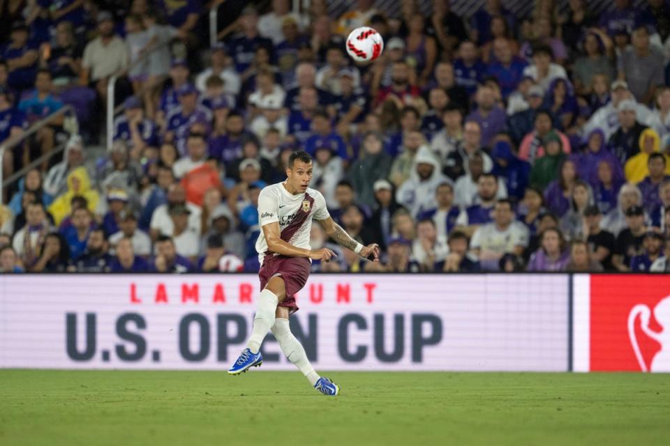 A Sacramento Republic player sending a ball forward with crowd in background