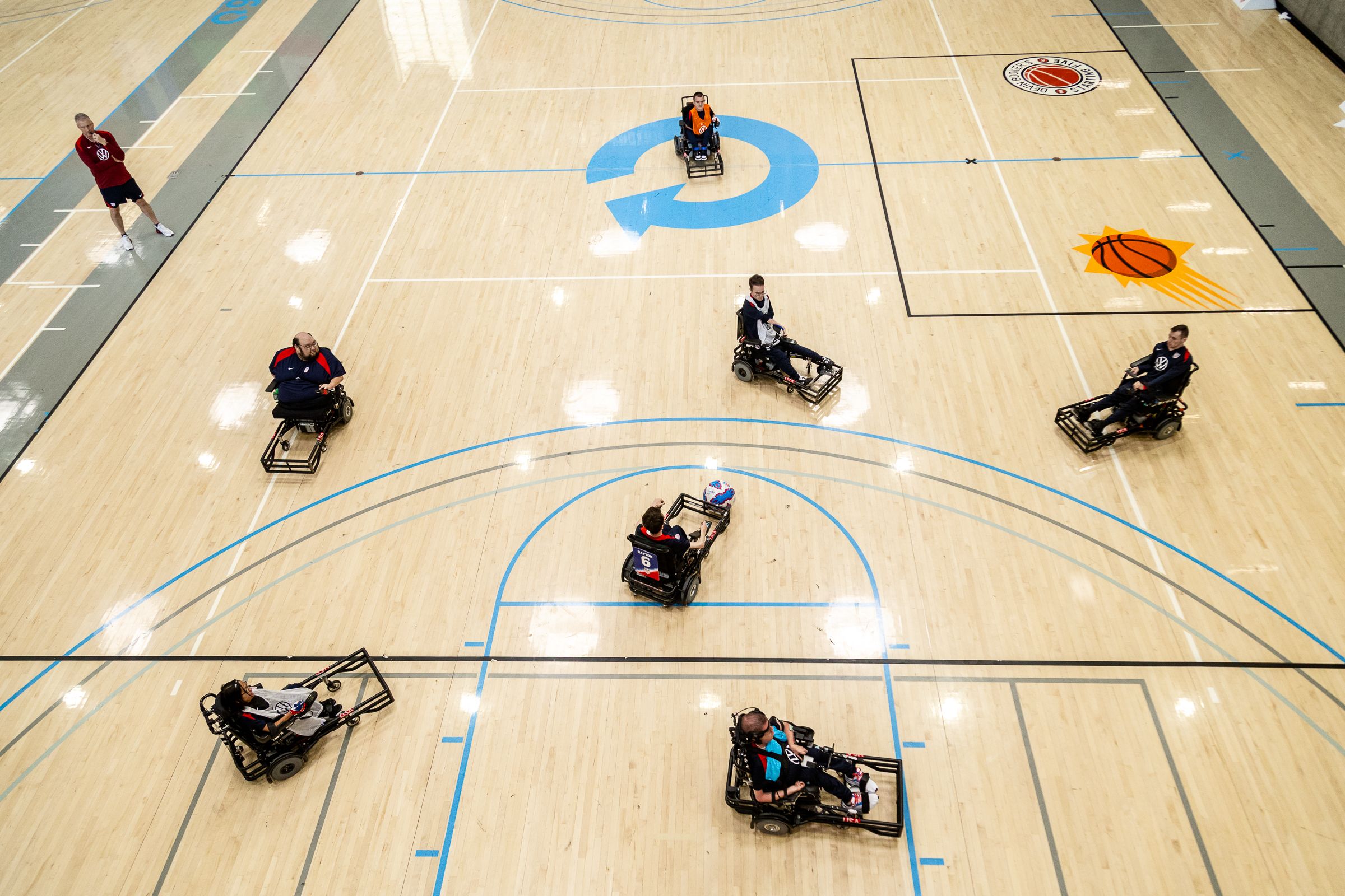 A group of people playing wheelchair soccer on an indoor court.