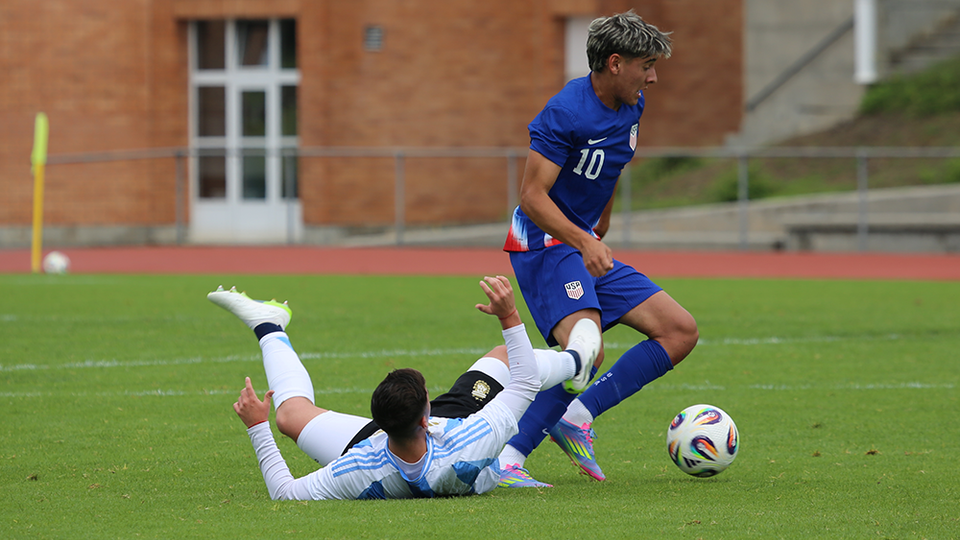 U18 player tackles ball away from defender