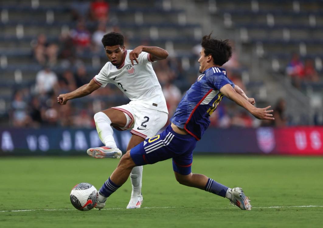 a usa player in white and japan player in blue fight for the ball