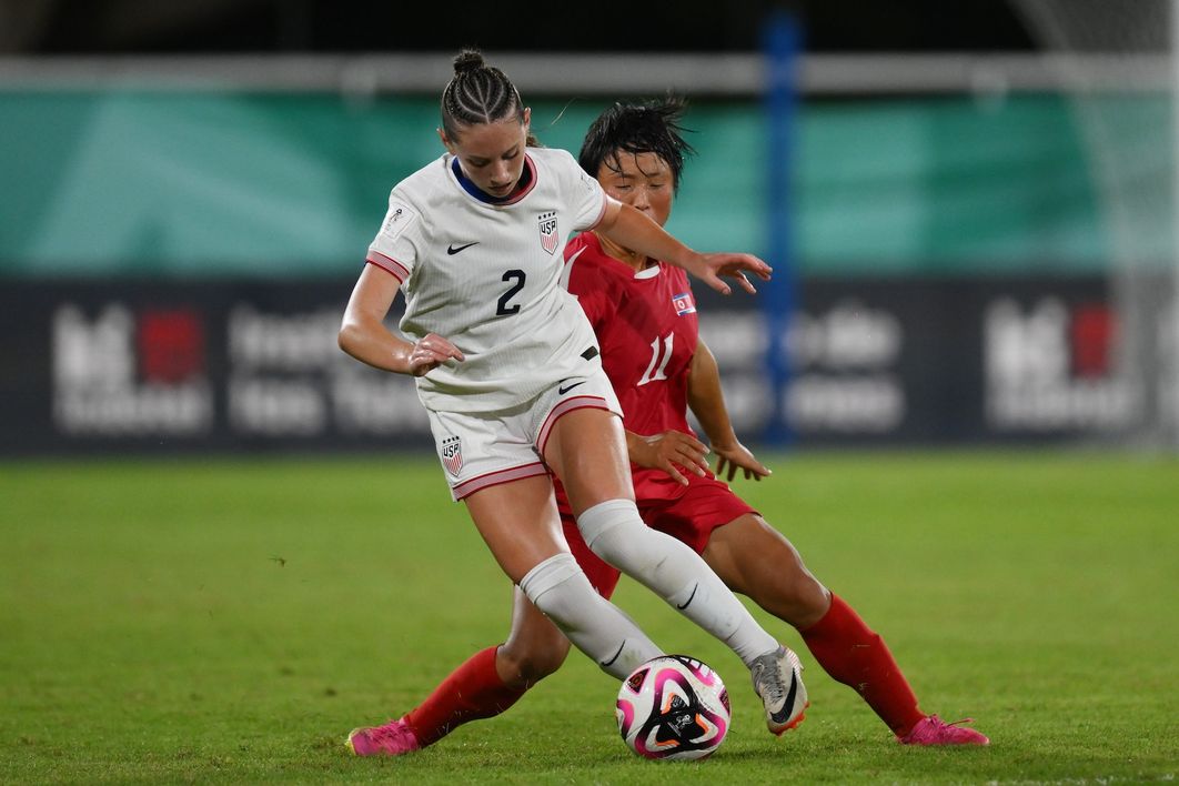 A U-17 player dribbles the ball past a Korea DPR player during a match