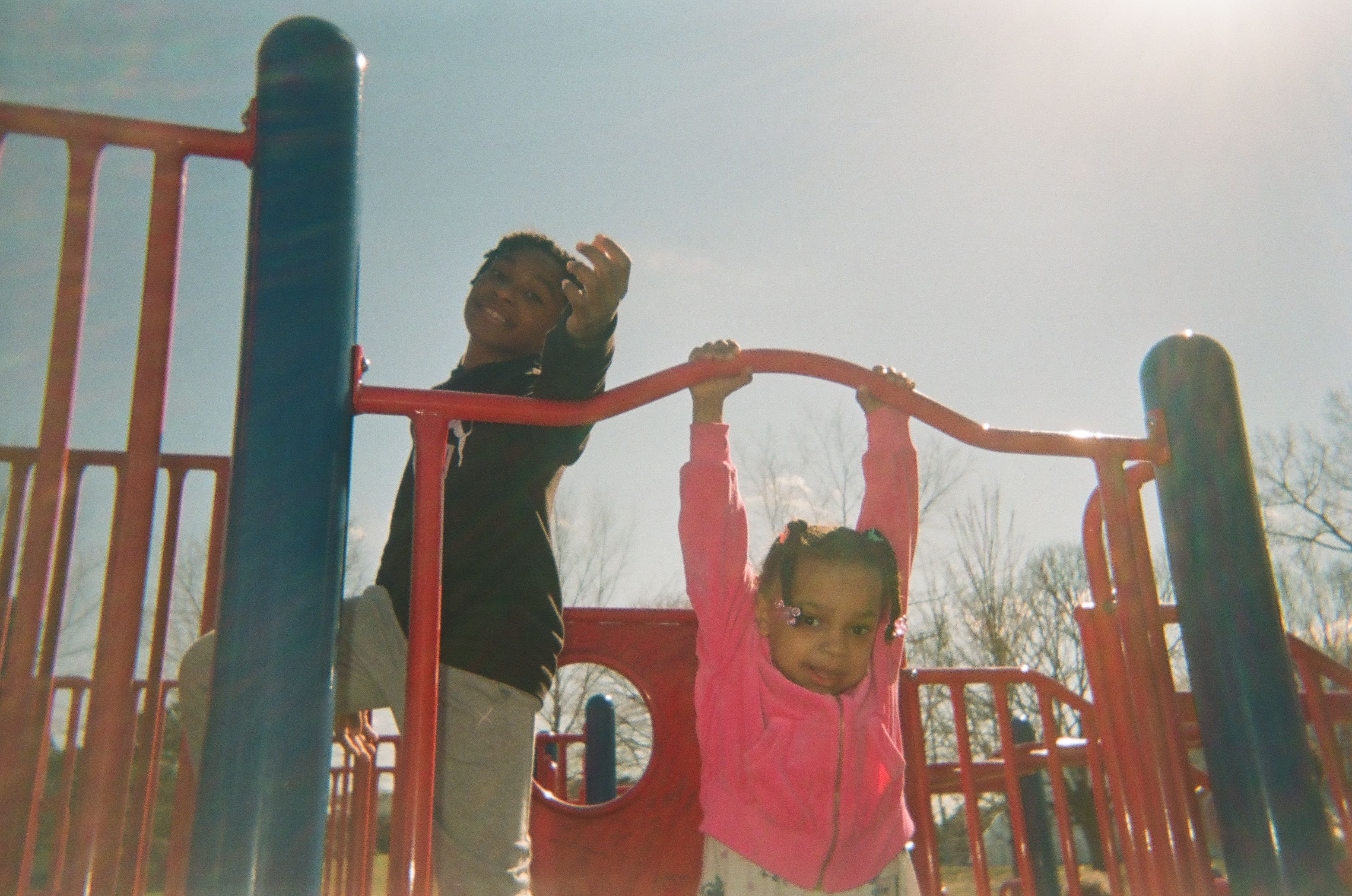 A young girl playing on climbing frame at a playground.