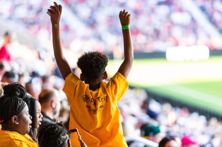 A child raises arms in the air to celebrate during a soccer match