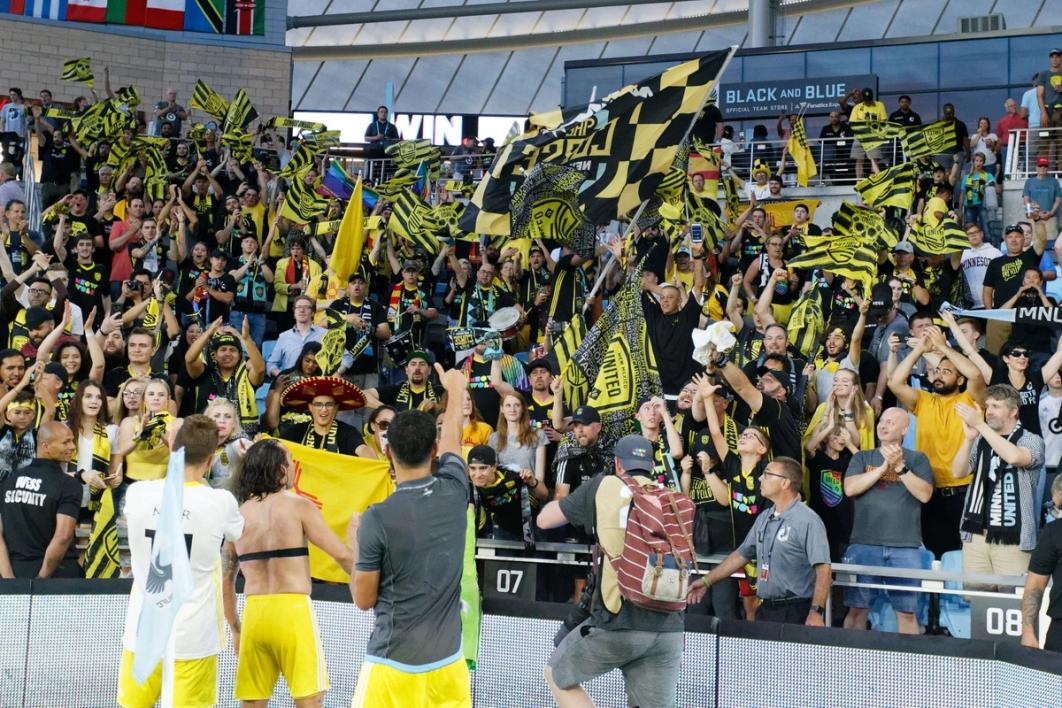 NMU players approach and celebrate with the crowd during a match