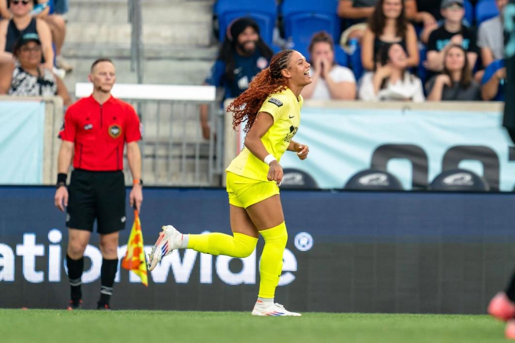 Trinity Rodman in yellow runs down the field and celebrates during a NWSL Match