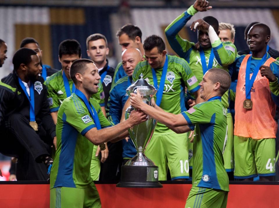 Clint Dempsey hands Ozzie Alonso the Open Cup trophy in 2014 with Seattle Sounders players in the background