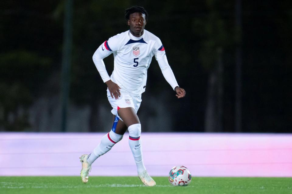 number 5 in white kit dribbles ball