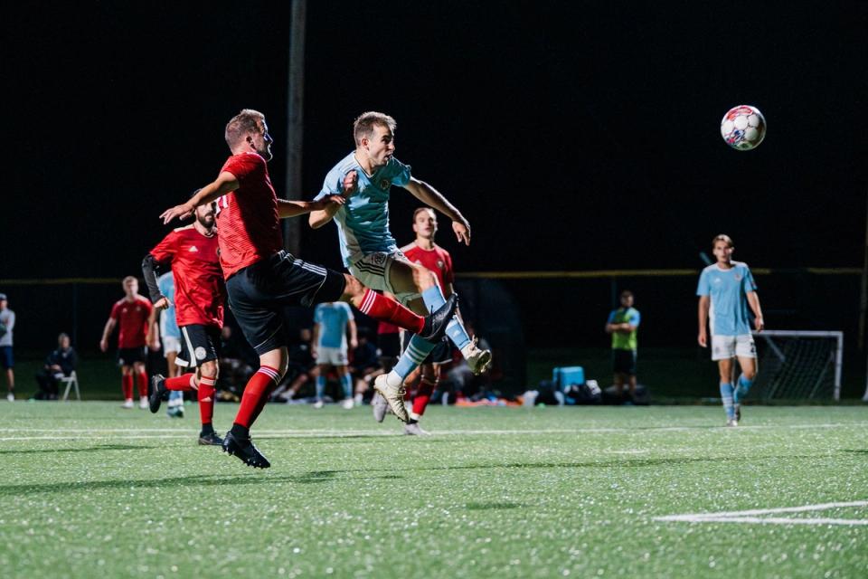 A West Chester United SC player and United German Hungarians player tangle up for an aerial ball during a match