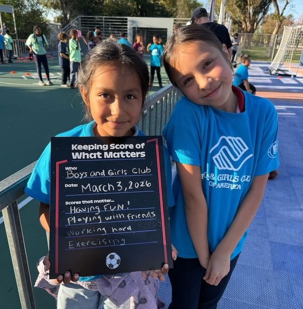Two girls holding a blackboard that says keeping score of what matters.