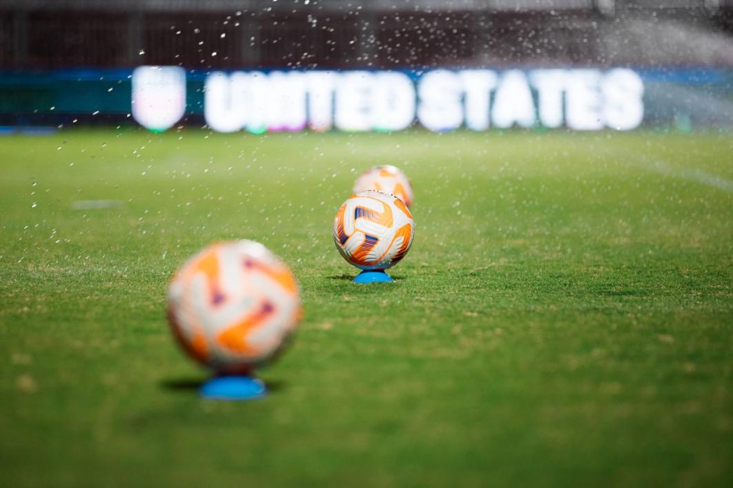 three soccer balls on a field
