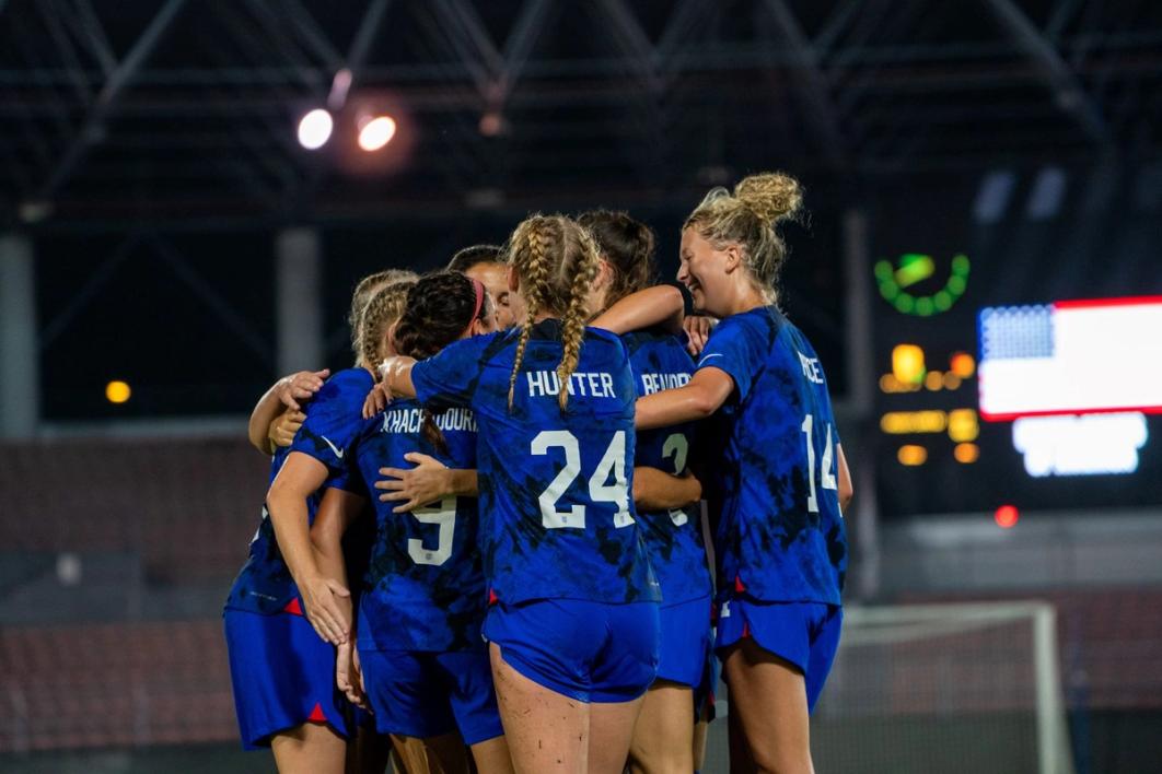 Seven Deaf Womens National Team Players huddle up in blue jerseys and shorts on a field