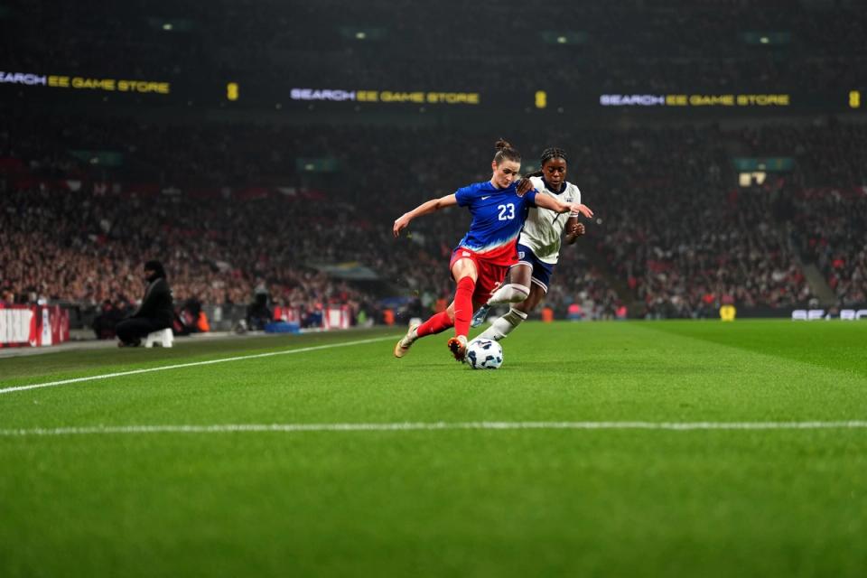 Emily Fox dribbles the ball around an England player at Wembley Stadium