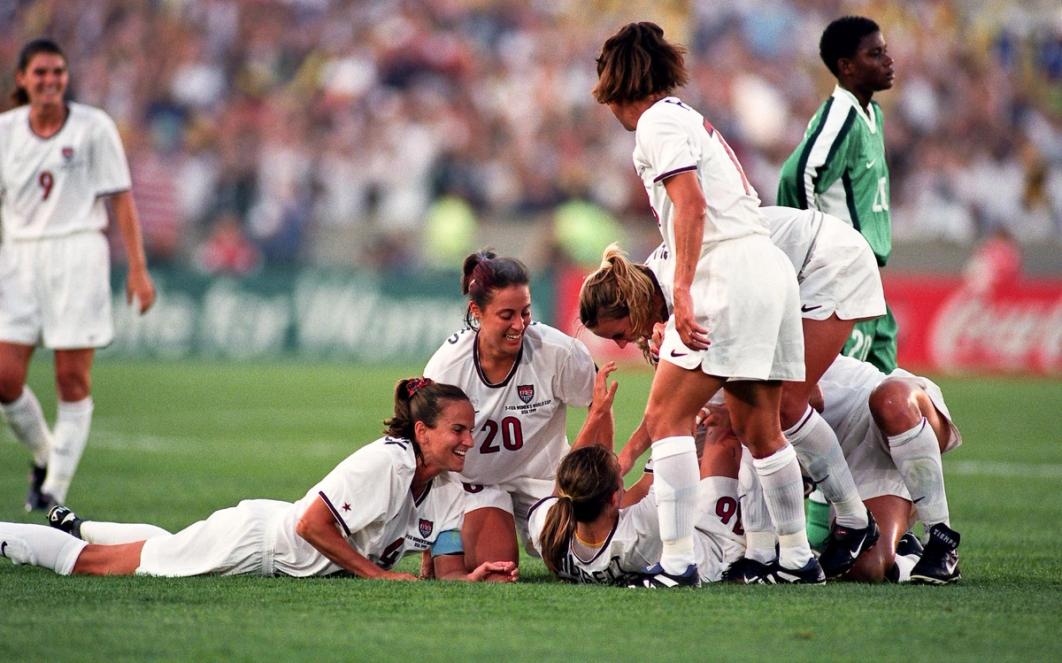 Seven USWNT players in white celebrate on the field during a 1999 Womens World Cup match against Nigeria