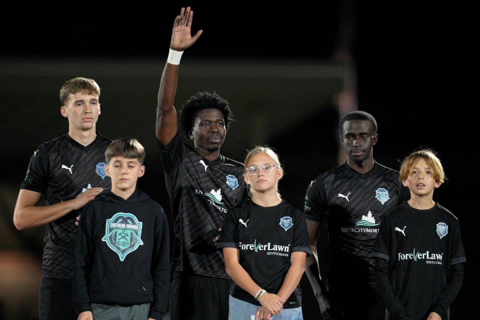 Players during a 2025 US Open Cup Qualifying Match stand at midfield with children in front of them