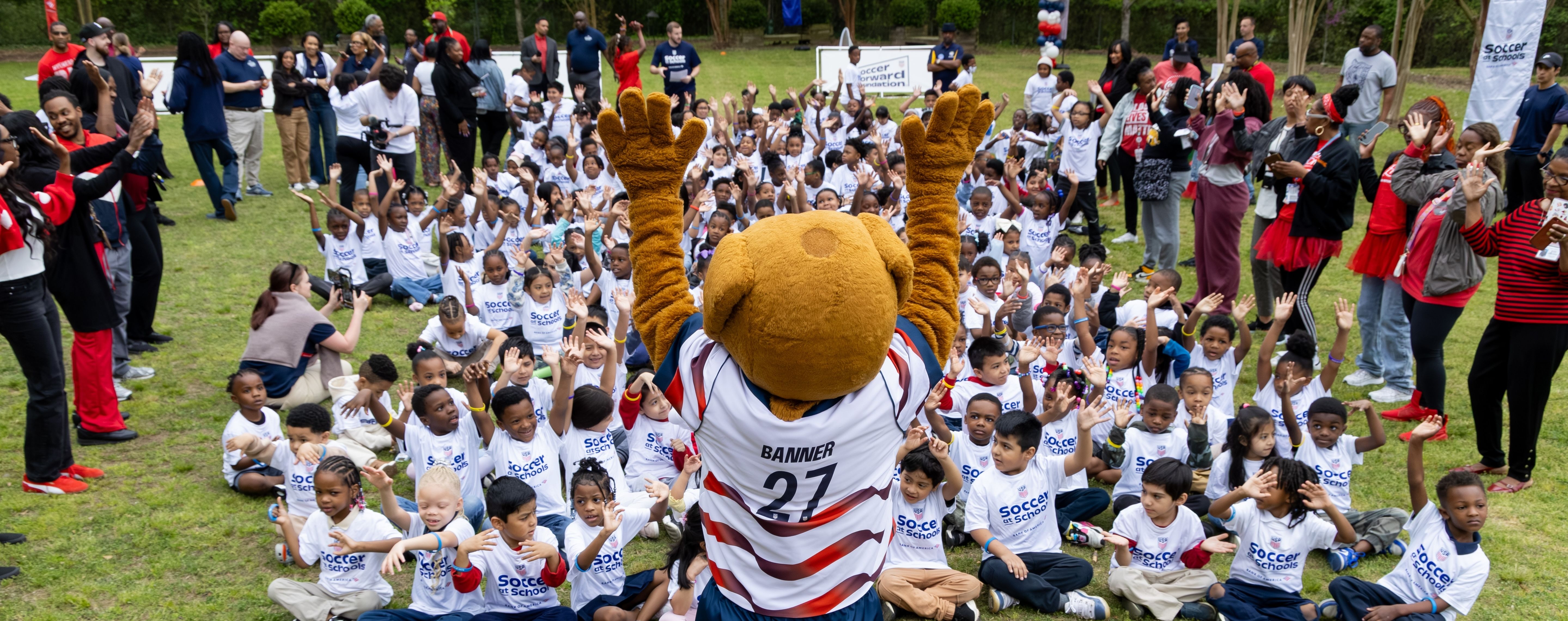 Banner the mascot celebrating soccer at schools with a group of kids