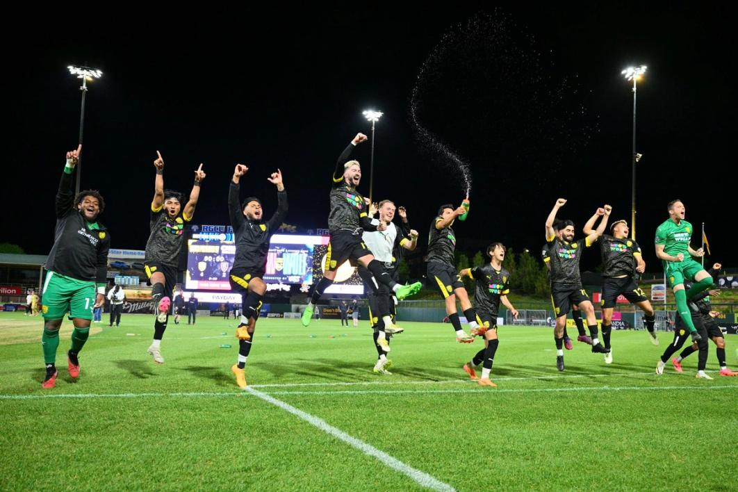 New Mexico United players celebrate on the pitch with jumping and spraying water from bottles