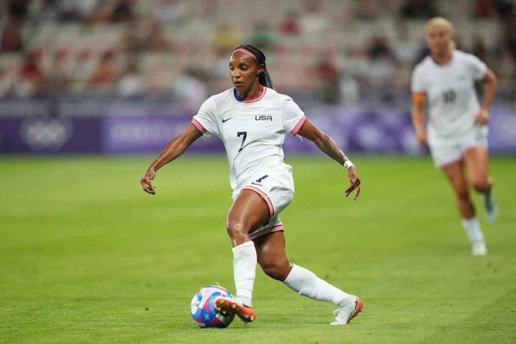 Crystal Dunn dribbles a ball with Lindsey Horan trailing in the background against Zambia