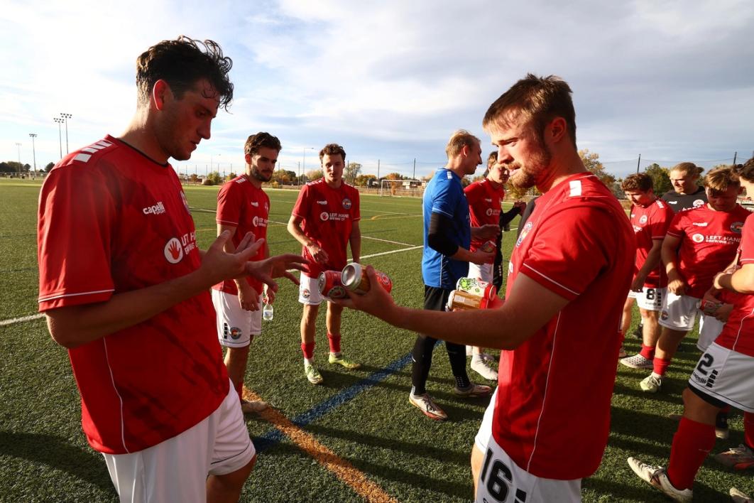 Two teammates in red on the sidelines during a 2025 Open Cup Match