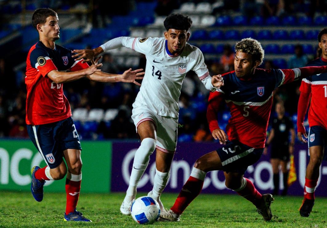Taha Habroune of the US U20 MYNT dribbles the ball between two Cuban defenders during a match