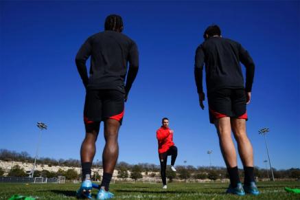 Two players listen to training instruction from a coach