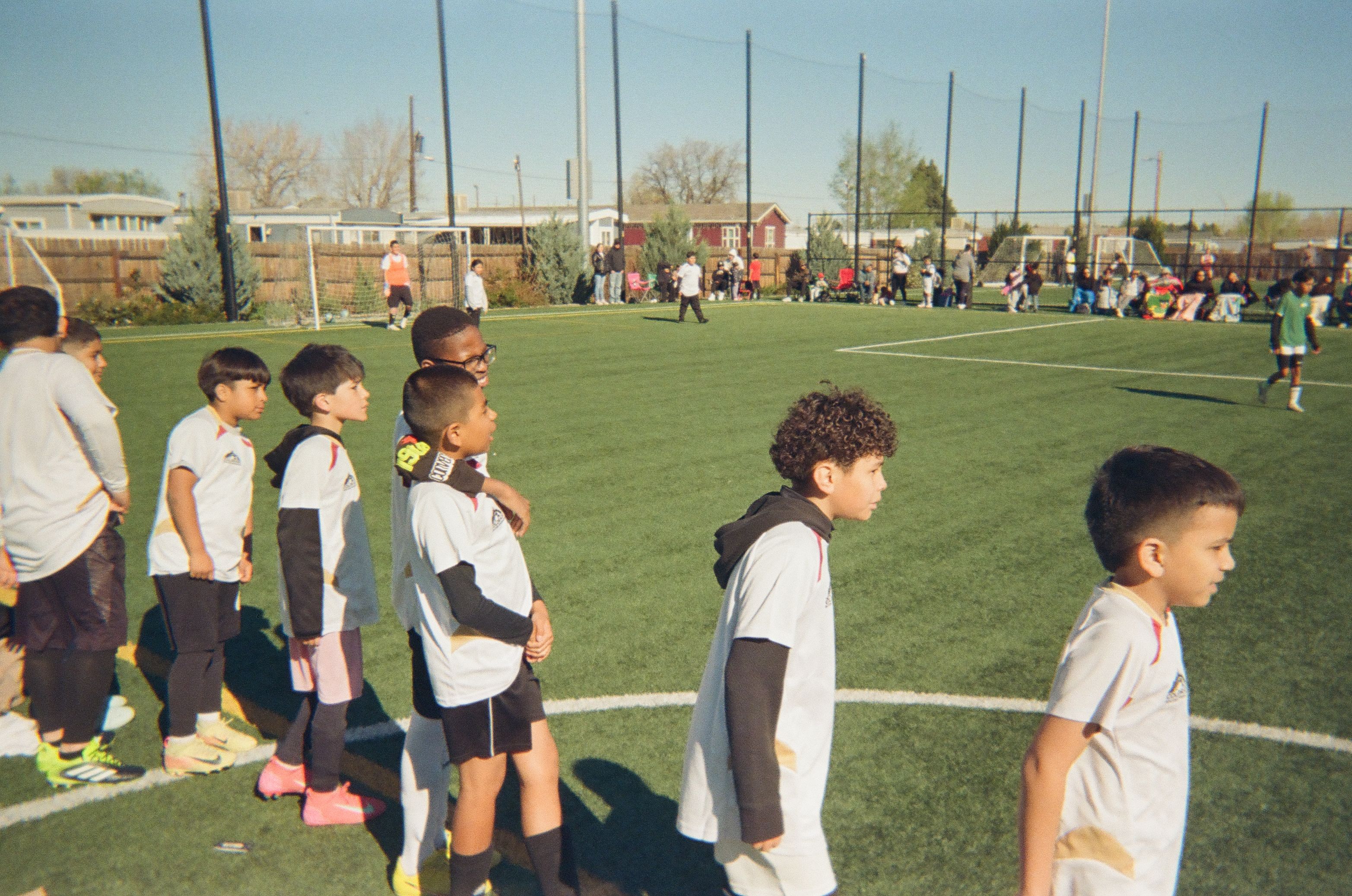 Youth soccer players lined up on the sideline during a community soccer match.