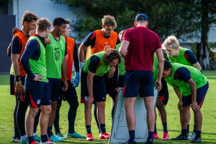 A group of players surround a coach and a whiteboard