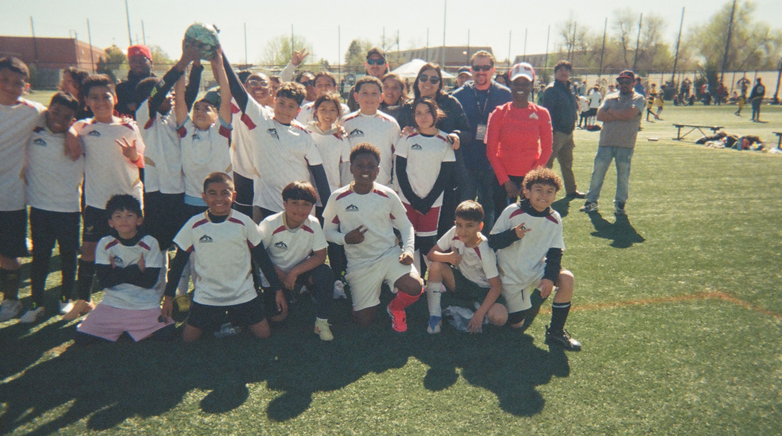 Youth soccer team posing together with coaches and community members at Colorado Soccer Foundation.