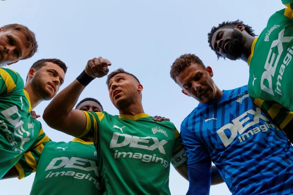 Six players in Tampa Bay Rowdies jerseys huddle up at a soccer match
