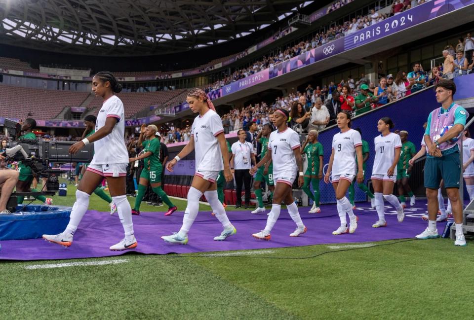 Naomi Girma, Trinity Rodman, Crystal Dunn, Mallory Swanson and Sophia Smith of the USWNT walk out of a tunnel and onto the field during a match
