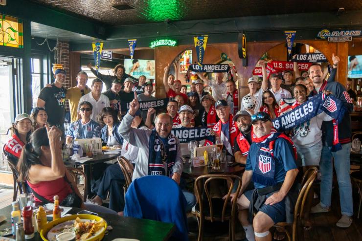 Group of U.S. Soccer fans posing inside a sports bar with USA jerseys and Los Angeles Insiders scarves.
