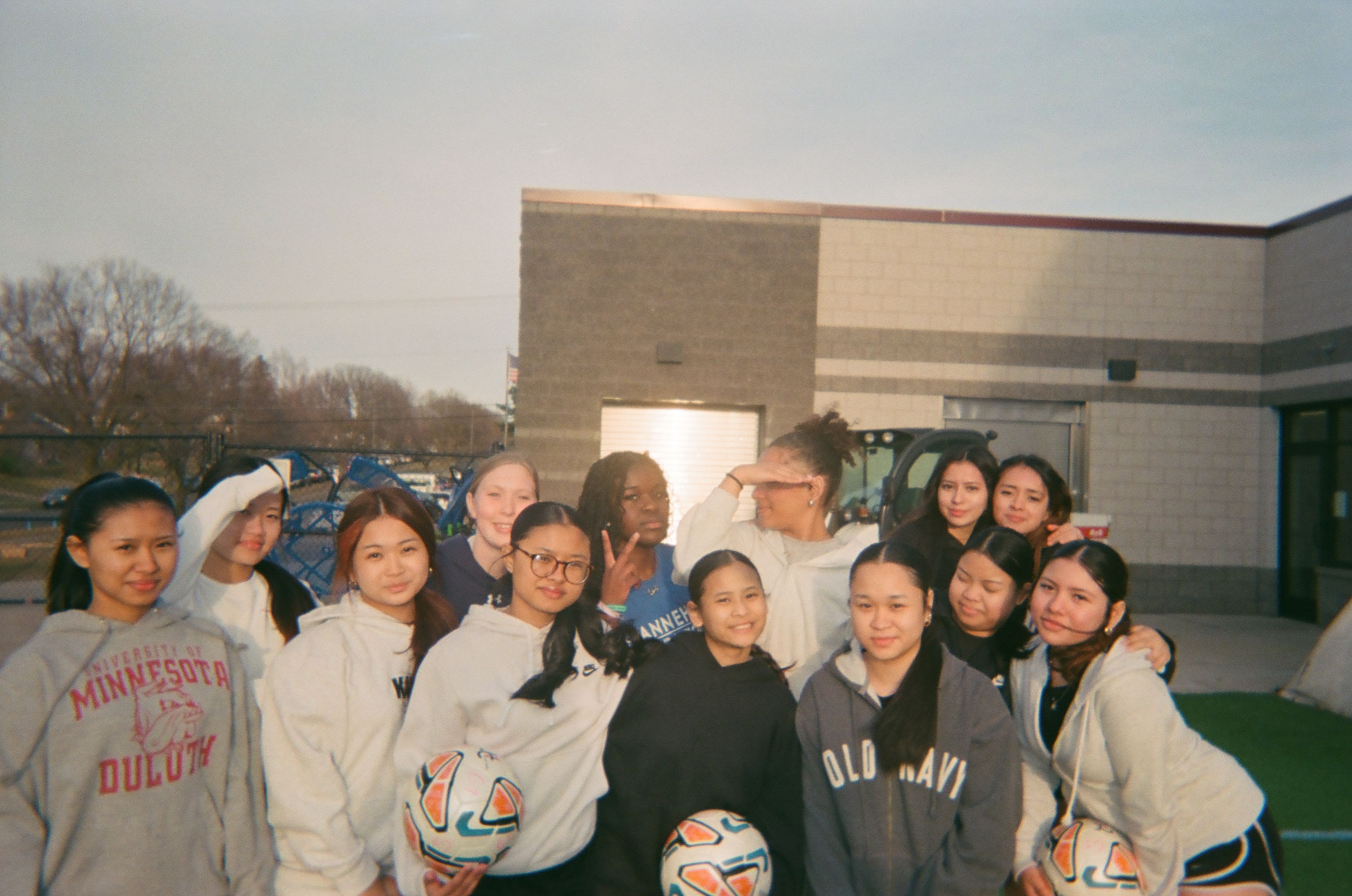 A group of girls holding soccer balls and posing for a group photo.