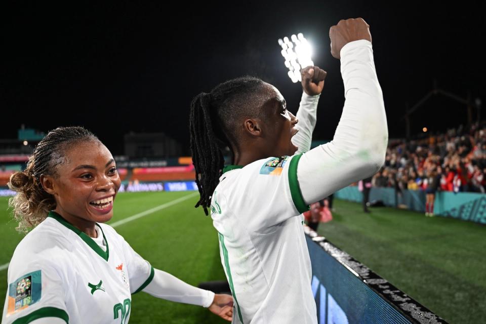 Two players on the Zambia National Team celebrate facing the crowd during a match