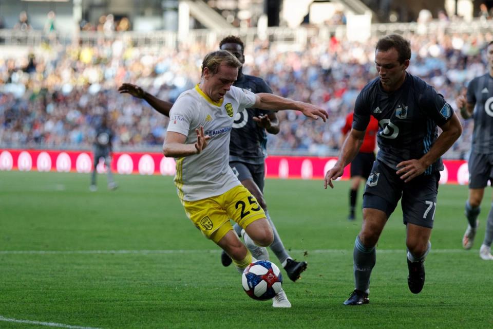 Daniel Bruce in White and Yellow dribbling the ball against Minnesota United