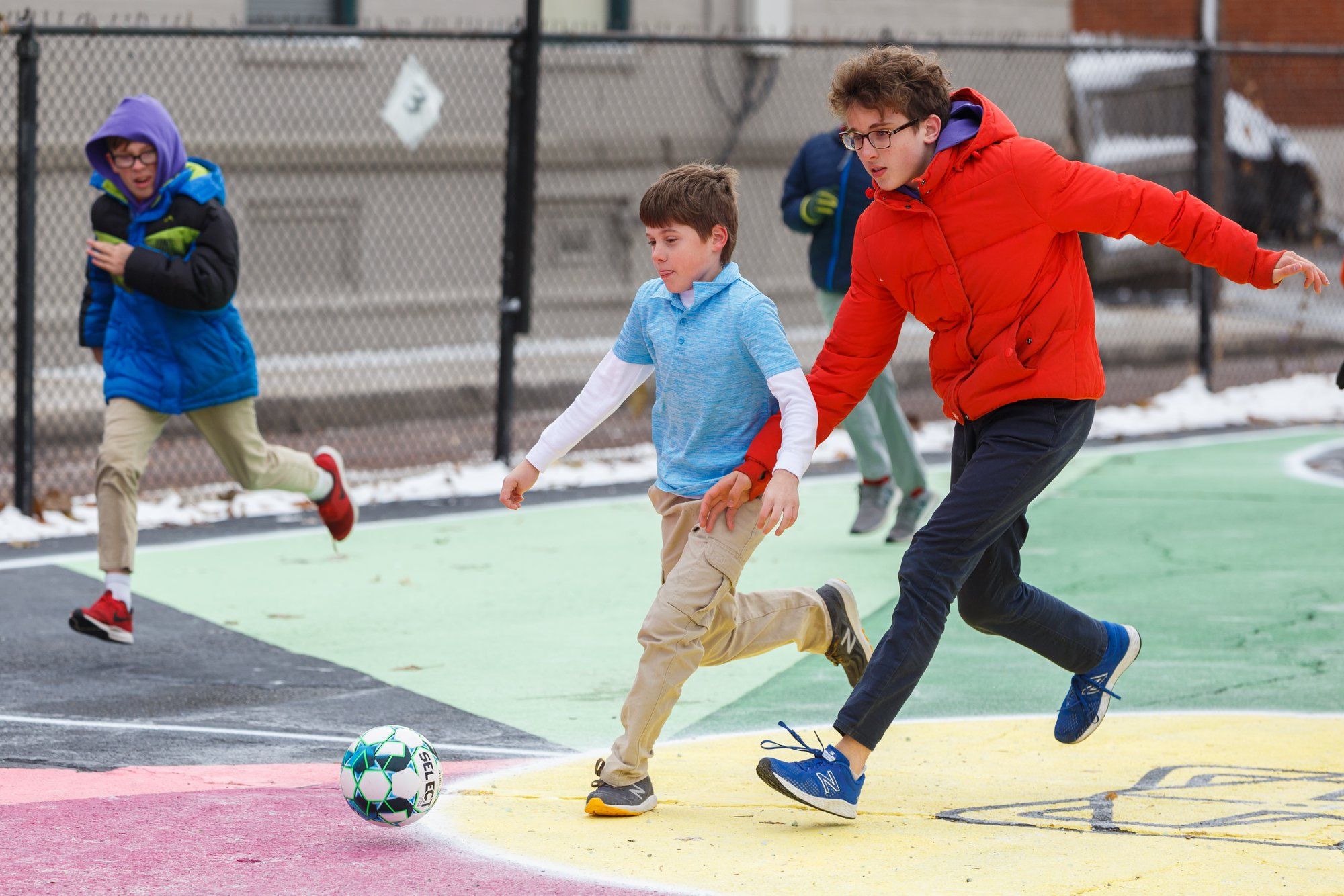 Two children chasing a soccer ball on a soccer field during a training session.