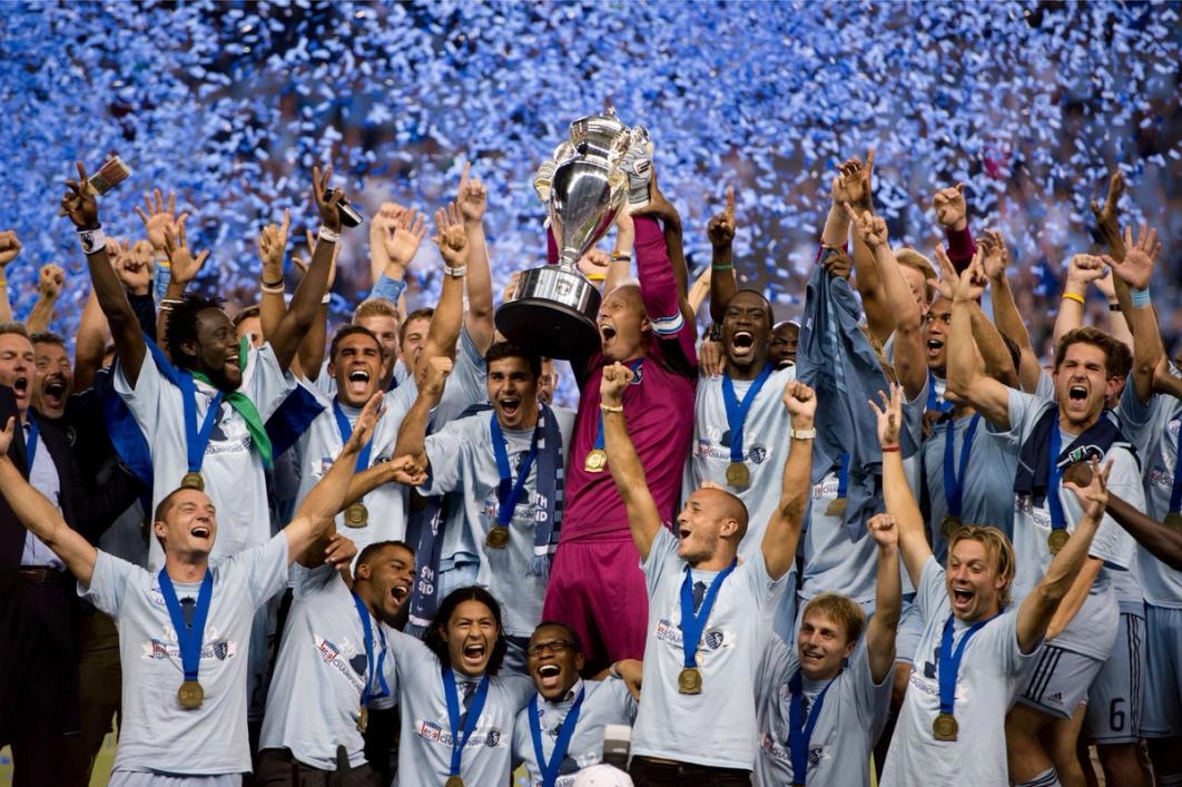 Sporting Kansas City players lifting the Open Cup trophy and cheering with confetti in background