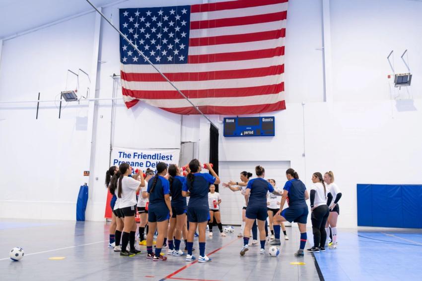 Futsal players on a court with a large american flag overhead