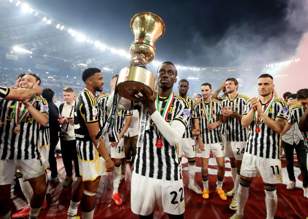 Tim Weah holds the Coppa Italia trophy and looks up towards the crowd