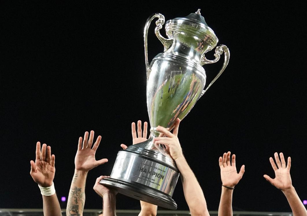 The US Open Cup Trophy is hoisted in the air by players