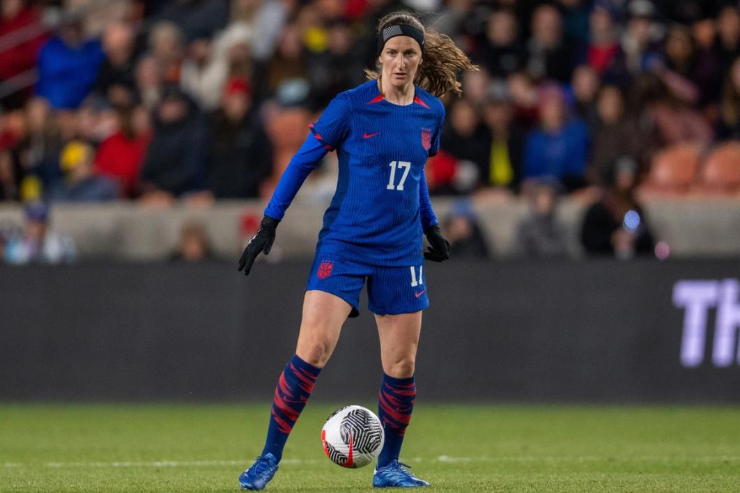Andi Sullivan dribbles the ball in a blue kit and shorts during a match