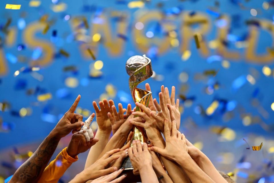 Photo of hands holding World Cup trophy as confetti falls
