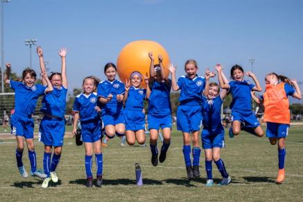 A group of young soccer players celebrates on a field