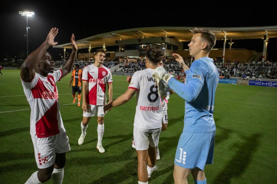 Four players high fiving and celebrating on the field
