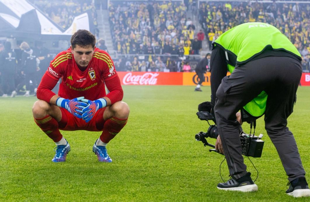 Schulte crouched on a field with a camera recording