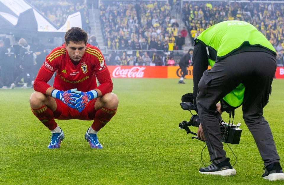 Schulte crouched on a field with a camera recording