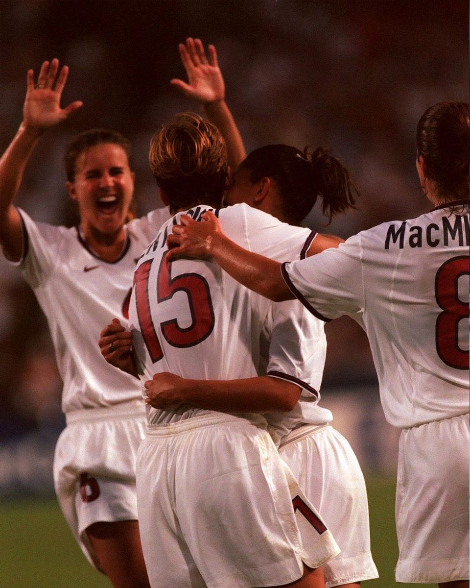 A group of four USWNT celebrates during a 1999 Womens World Cup match