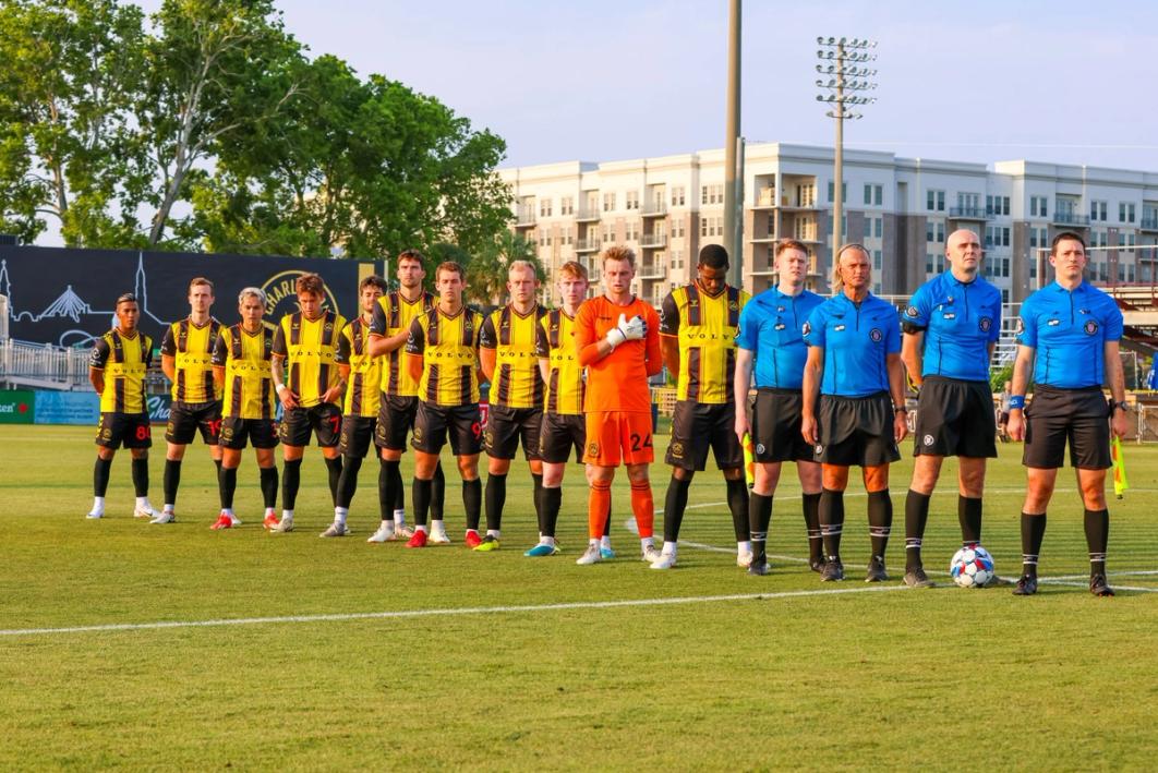 The Charleston Battery Starting 11 and four referees stand at midfield during the national anthem