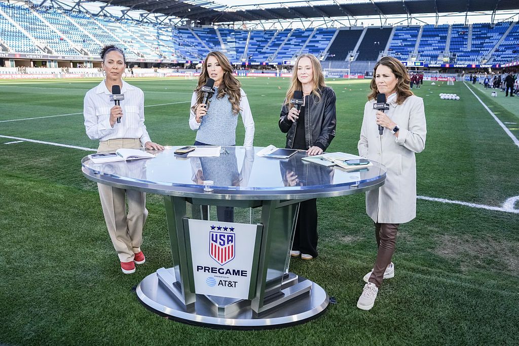 Shannon Boxx Sara Walsh Becky Sauerbrunn Julie Foudy standing around the broadcast desk holding mics on the field during a live show